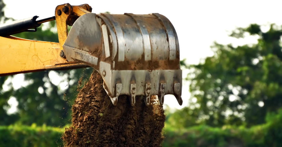 an excavator arm unloading dirt