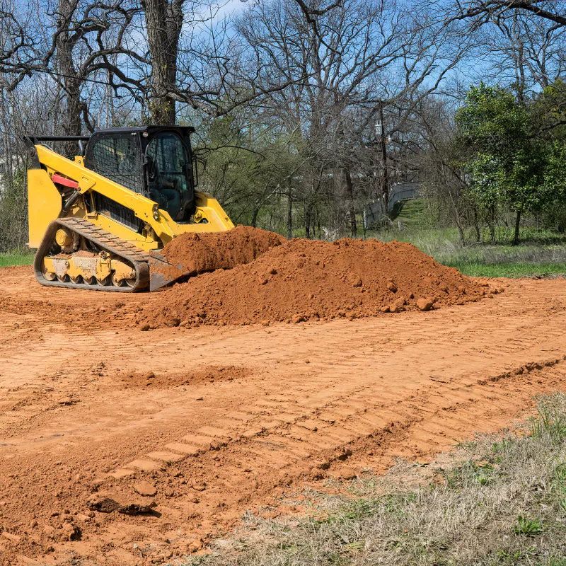 mini front loader piling up dirt in an area